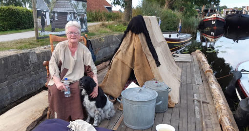 Vrijwilligers Damhûs varen met vlot op palen mee met de turfvloot